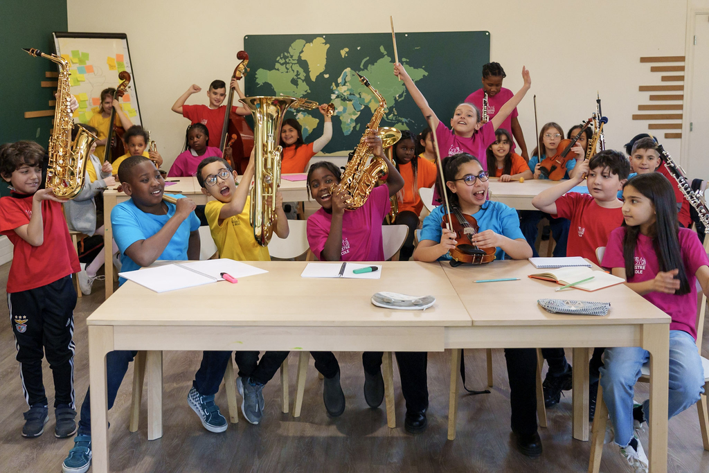 Classe d'enfants montrant chacun fièrement leur instrument et habillés d'un T-Shirt coloré uni Orchestre à l'Ecole