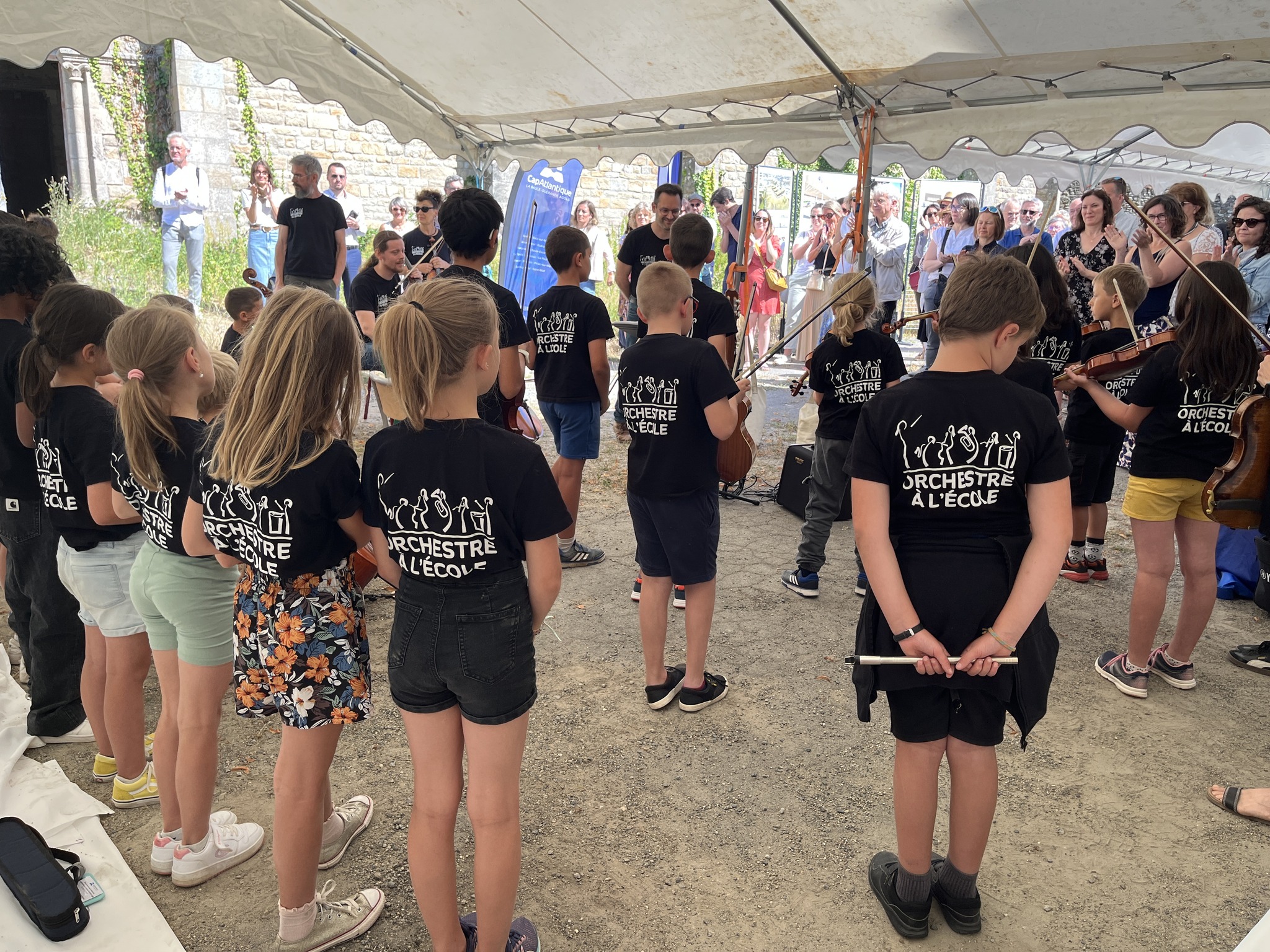 Les élèves de l'orchestre à l'école de dos lors de la cérémonie de la pose de la première pierre du futur conservatoire à Guérande en juin 2025.