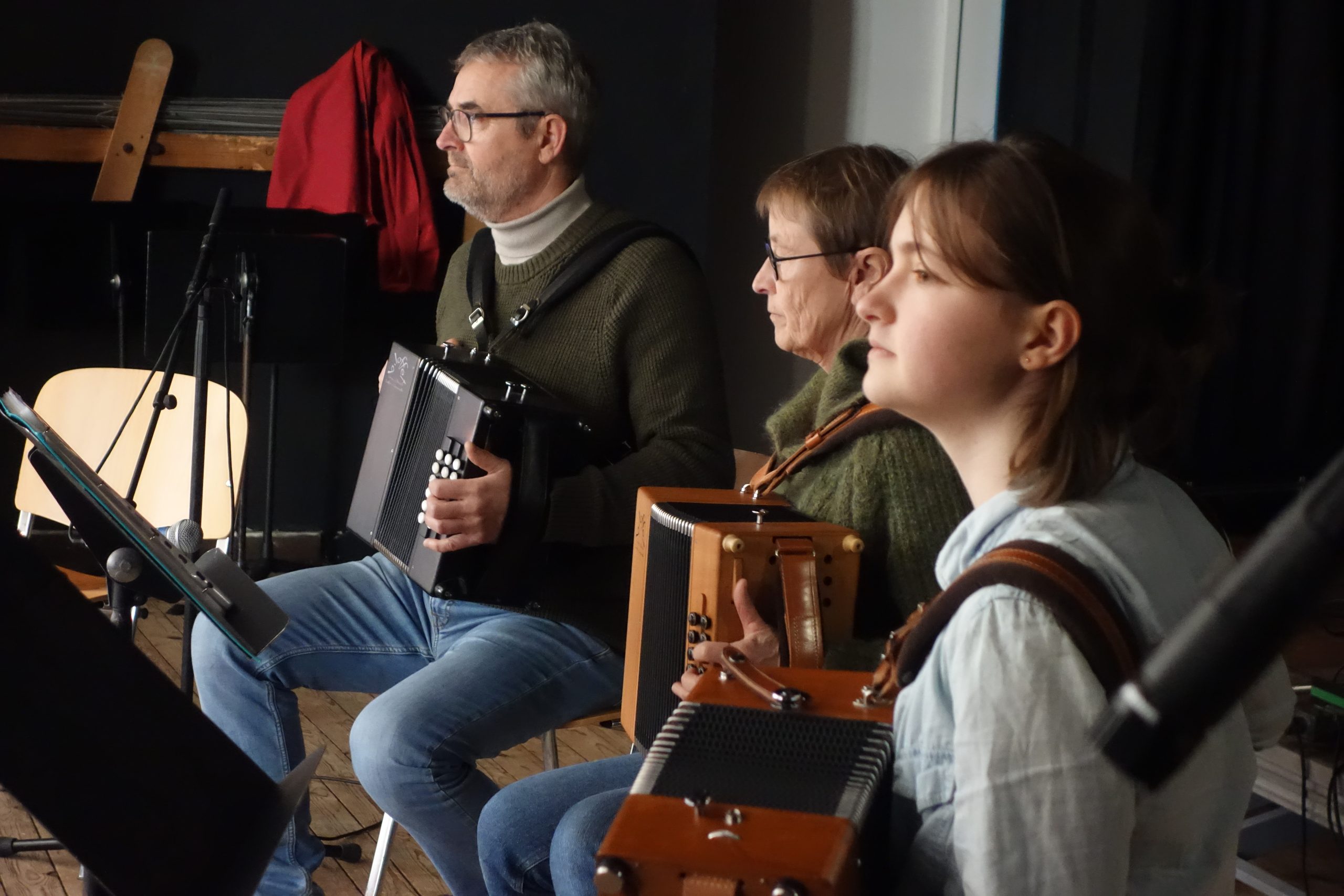 2 élèves accordéonistes avec leur enseignant sur scène.