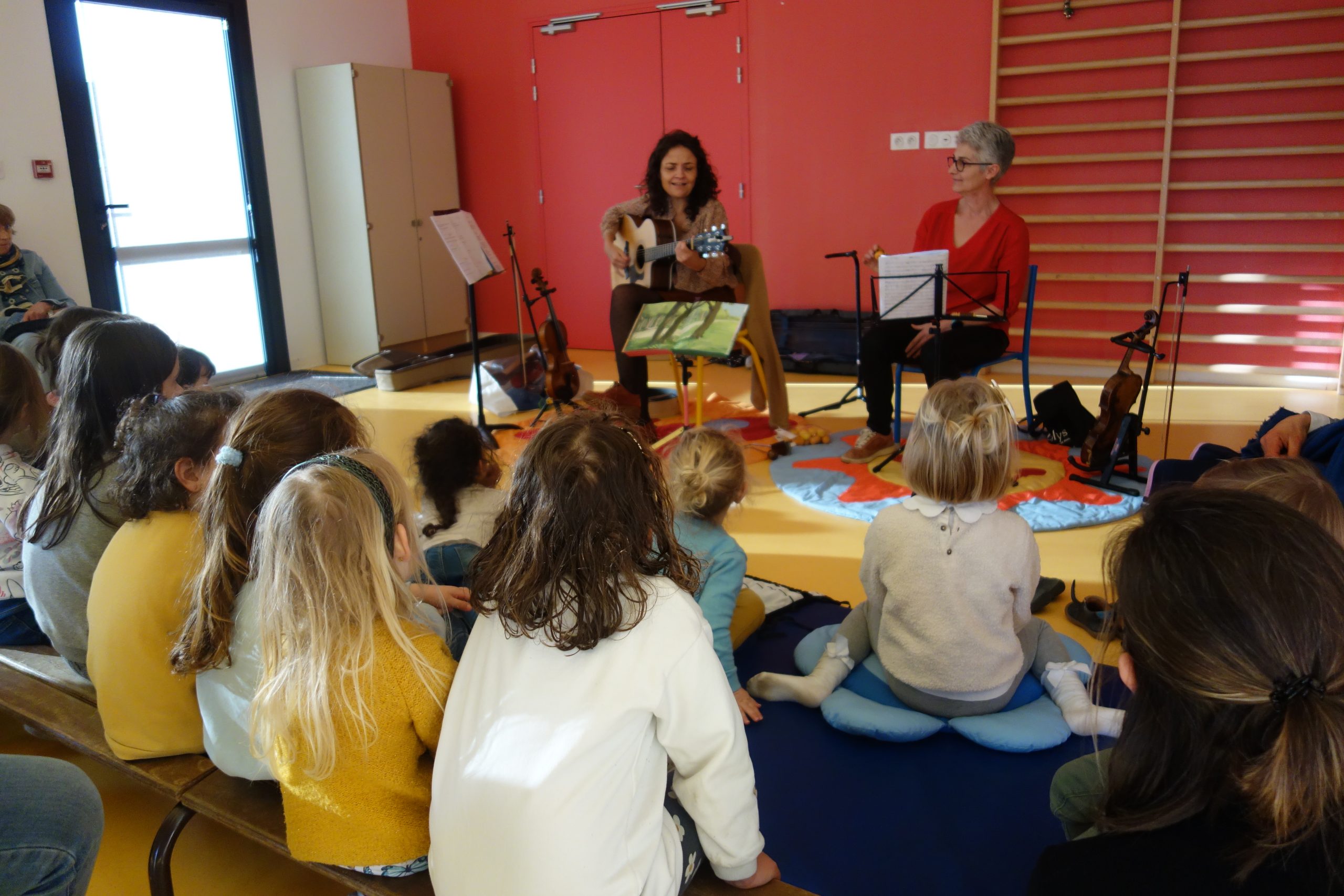 Deux enseignantes en représentation devant un très jeune public assis.
